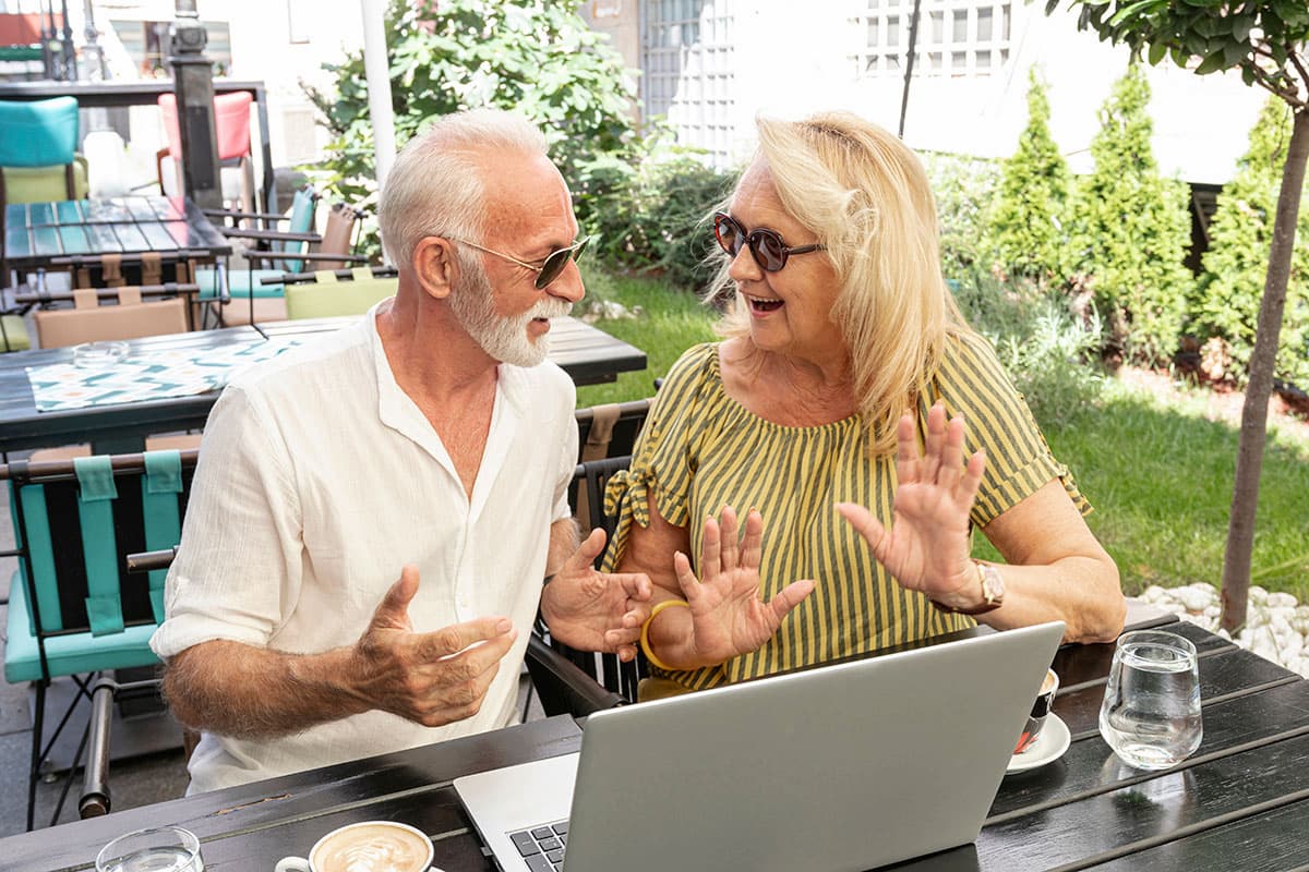 Older couple laughing together as they look at a laptop screen
